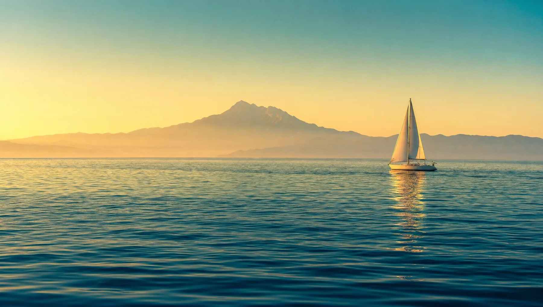White sailing boat with Mount Athos on the horizon